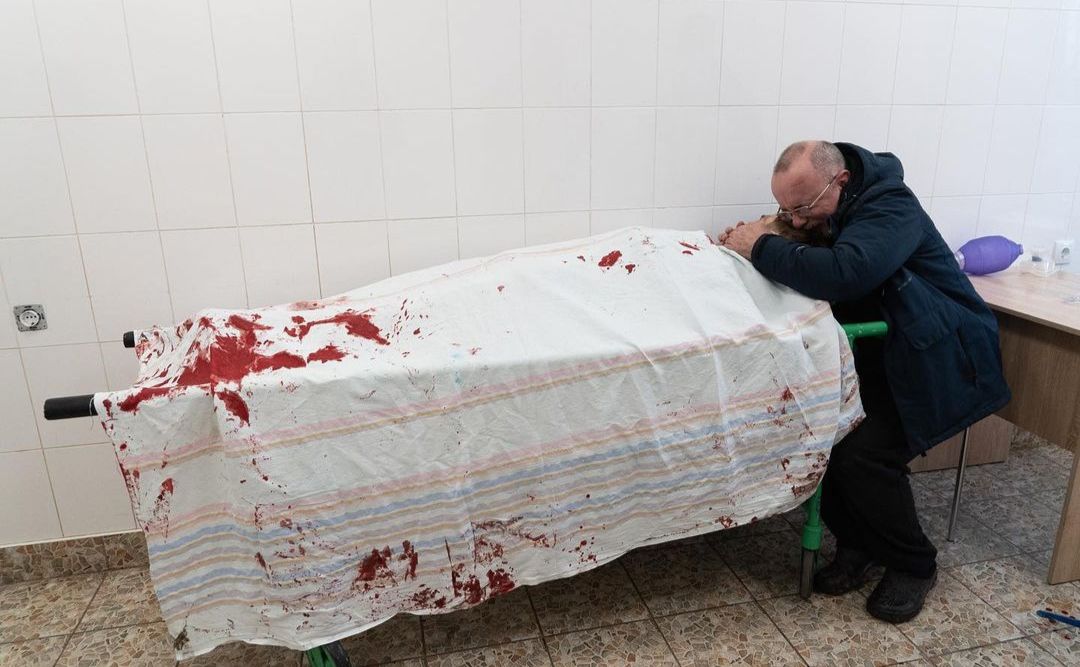 На фото батько підлітка плаче на тілі сина, який лежить на ношах у лікарні в Маріуполі. Фото: mstyslav.chernov