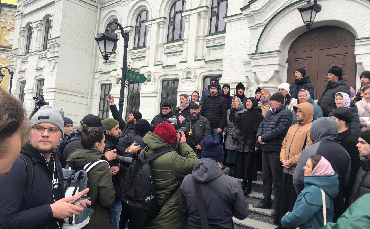 Біля входу до храму Агапіта Печерського на території лаври стоять віряни проти членів комісії МКІП. Фото: Фейсбук
