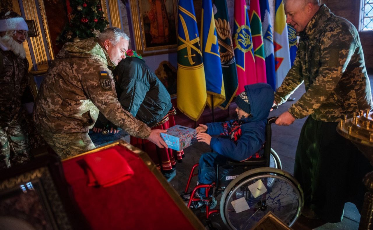 Сергій Наєв вручає подарунок дитині до зимових свят. Фото: Фото прес-центру КОС ЗСУ