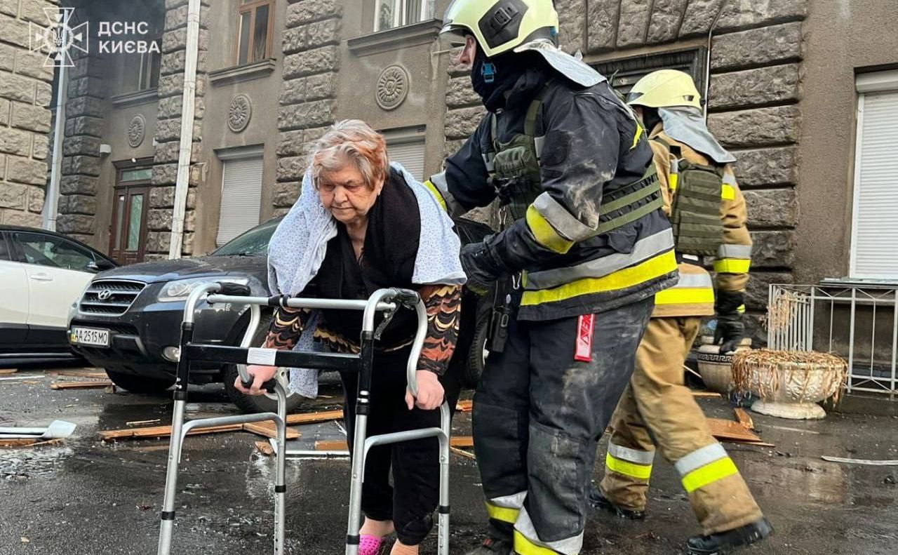 Рятувальники допомагають літній жінці вийти з пошкодженого буинку на Печерську. Фото: ДСНС