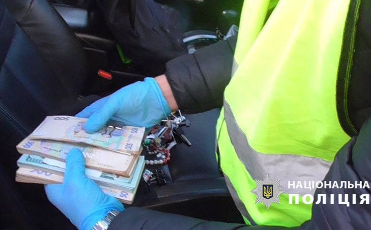Поліція з коштами, знайденими у зловмисників. Фото: Нацполіція