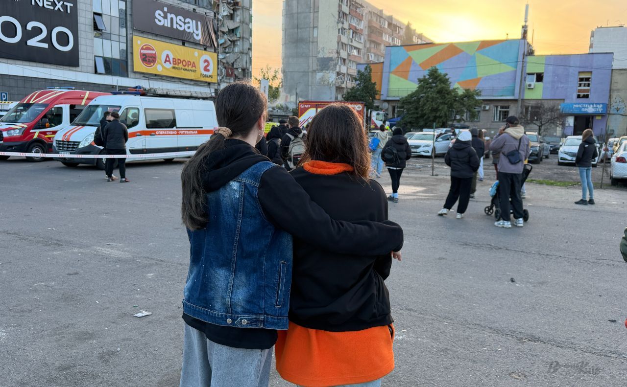 Мешканці зруйнованої частини будинку дивляться на свій колишній дім у Дарницькому районі Києва. Фото: Даша Гришина