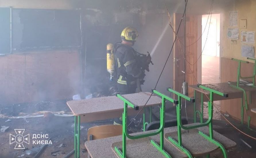 Рятувальник гасить пожежу після російської атаки на заклад освіти. Фото: ДСНС Києва